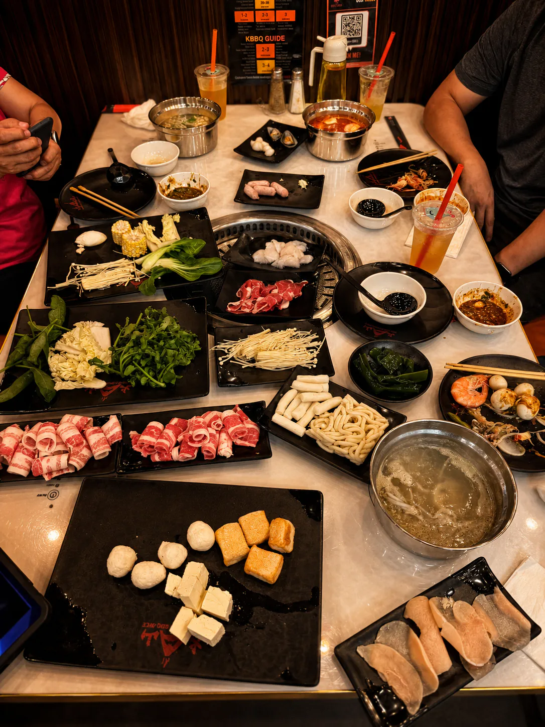 Hot Pot and BBQ Feast with sliced meats, seafood, vegetables, noodles, and dipping sauces